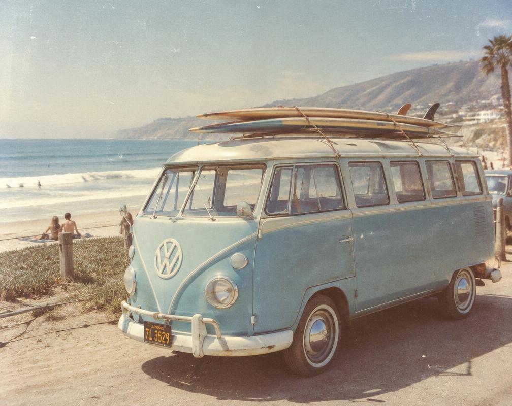 Pale blue vintage van with longboards parked by the beach